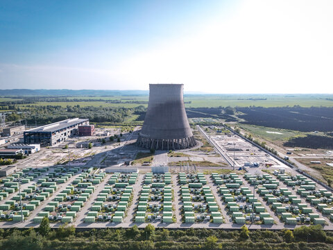 Aerial view of the former nuclear power plant cooling tower surrounded by a large-scale photovoltaic solar park, representing the energy transition in Trino, Piedmont, Italy.