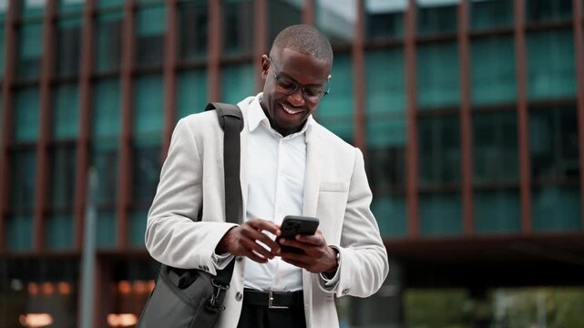 Black businessman, using smartphone, messaging client, outdoor near office building. African american business man smiling, works as startup founder, prepared for client meeting, managing accounts.
