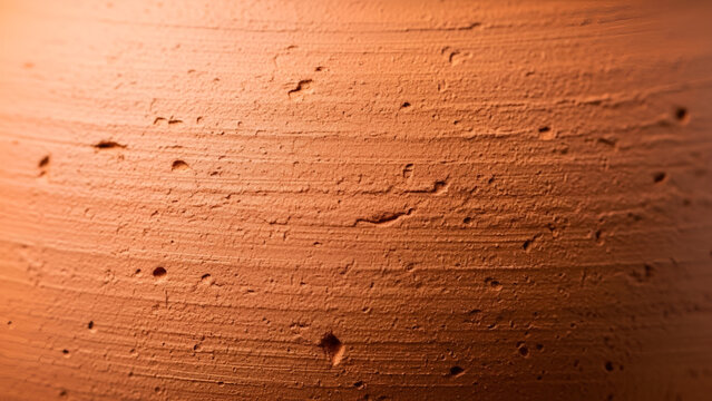 Rough textured terra cotta surface showing organic clay details with warm natural lighting and depth