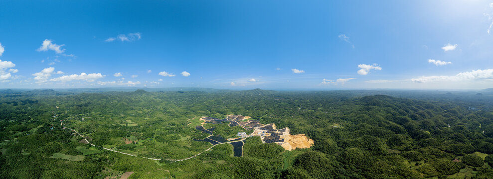 Aerial view of Sikatuna Solar Power Plant nestled within the lush green rolling hills of the landscape in Sikatuna, Central Visayas, Philippines.