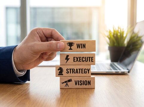 Businessman placing a wooden block labeled win on top of blocks labeled execute strategy and vision symbolizing business success