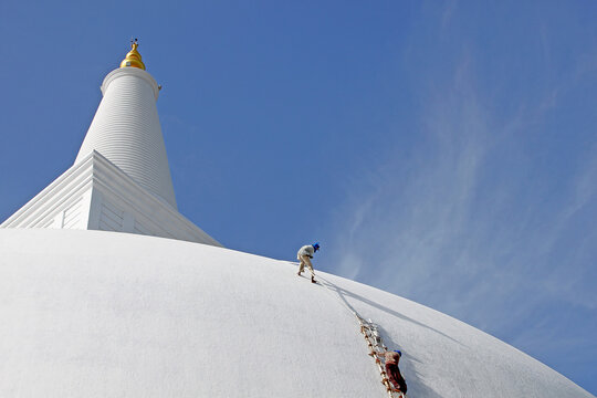 Workers Whitewashing Massive White Buddhist Stupa Dome under Blue Sky in Sri Lanka - Scale and Maintenance Concept Photography