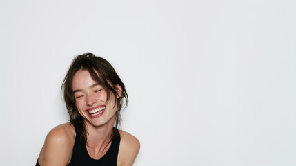 Fototapeta premium young european woman laughing with eyes closed in studio portrait