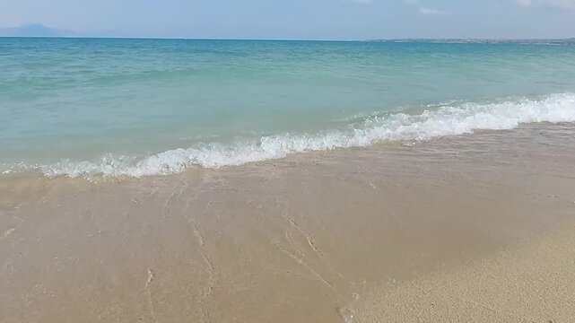 Scenic sandy beach and turquoise blue water waves on Lake Sevan Armenia. Beautiful tropical style sandy beach with gentle turquoise water waves rolling ashore at Lake Sevan in Armenia, sunny summer da