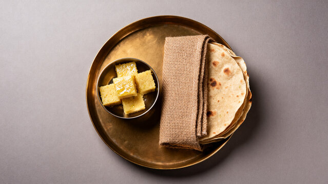 Copper tray with steamed dhokla and wrapped thepla, Indian snack preparation concept