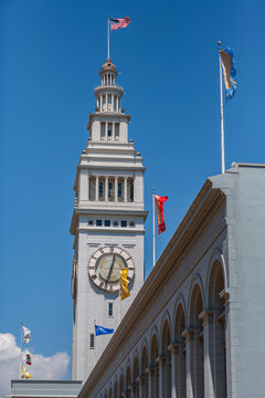 Vertical view of the historic Ferry Building clock tower with American flag in San Francisco