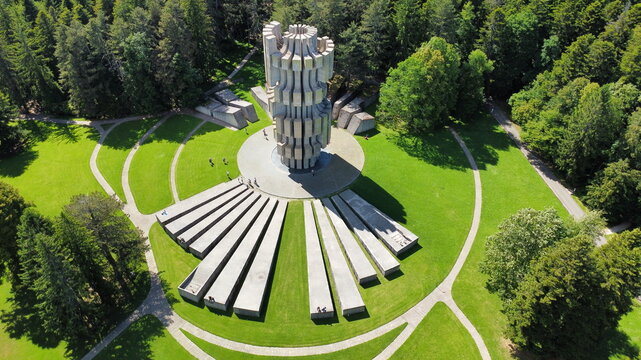 Aerial view of the Mrakovica monument in Kozara National Park, surrounded by lush green lawns, concrete pathways, and dense forest in Kozara, Republika Srpska, Bosnia and Herzegovina.