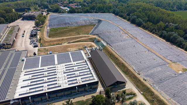Aerial view of biological waste treatment piles with aeration pipes at Cascina Maggiore facility featuring solar panels on industrial rooftops in Lacchiarella, Lombardy, Italy.