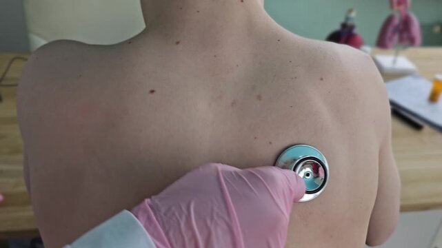Medical checkup with stethoscope on patient&rsquo;s back in clinic