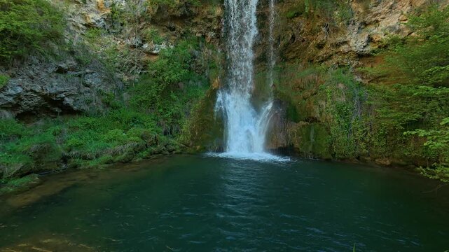 Waterfall cascades into a tranquil, deep green pool. Veliki Buk, Serbia.
