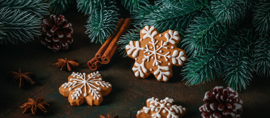 Gingerbread snowflakes with Christmas decorations and spices on a dark rustic background, selective focus, panoramic banner © Yulia