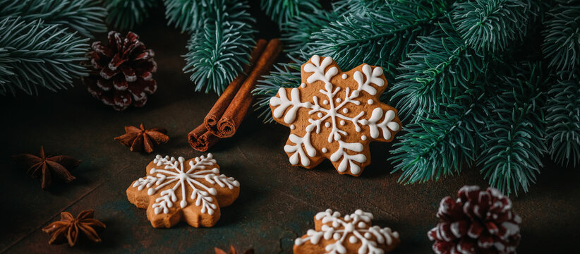 Gingerbread snowflakes with Christmas decorations and spices on a dark rustic background, selective focus, panoramic banner