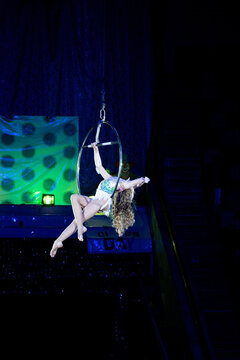 Girl doing aerial gymnastics stunt at World Circus Day event. Concept: Youth circus art development, Children sports hobbies, Aerial silk rings.
