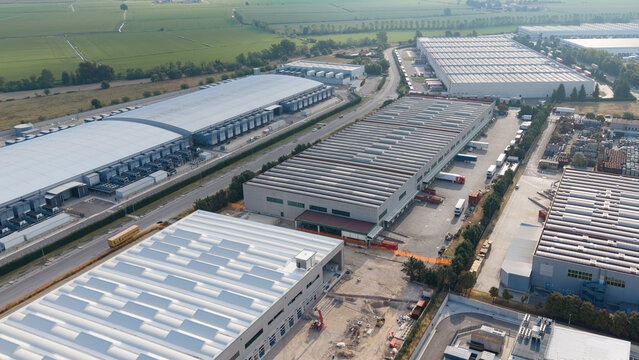 Aerial view of modern logistics warehouses and industrial facilities with large rooftops and loading docks in Siziano, Lombardy, Italy.
