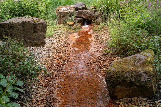 Red water flowing in rocky stream in bottrop