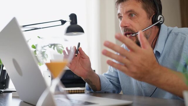 Business professional speaking emotionally during an online business conversation while wearing a headset. Crisis communication, conflict management, business pressure and workplace challenges concept