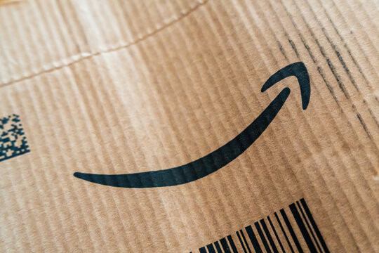 Warsaw, Poland - July 30, 2026: Amazon branded cardboard shipping box close-up showing iconic arrow logo and barcode on corrugated surface in natural light