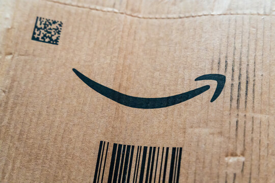 Warsaw, Poland - July 30, 2026: Amazon branded cardboard shipping box close-up showing iconic arrow logo and barcode on corrugated packaging surface