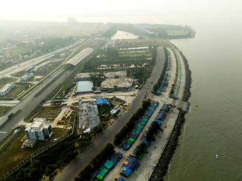 Aerial view of the coastal area in Chattogram featuring a long road, small market stalls along the waterfront, and urban infrastructure in Chattogram, Chittagong Division, Bangladesh.