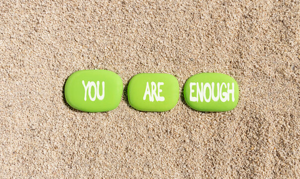 You are enough words symbol. Concept words You are enough on beautiful green stones. Beautiful sand beach background. Business motivational and you are enough concept. Copy space.
