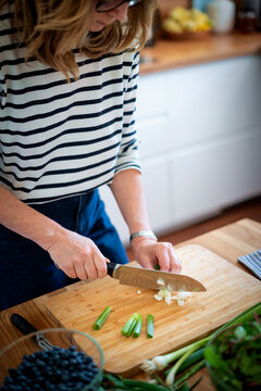 
Close up of woman's hands slicing fresh organic carrots on kitchen counter