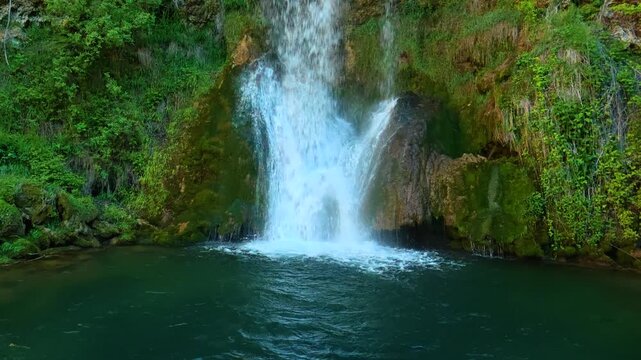 Waterfalls cascade over mossy rocks into a deep green pool. Veliki Buk, Serbia.