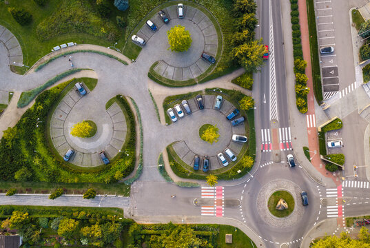 Aerial view of the unique circular parking lot design with parked cars, surrounding greenery, and a nearby roundabout in Sopot, Wojewodztwo pomorskie, Poland.