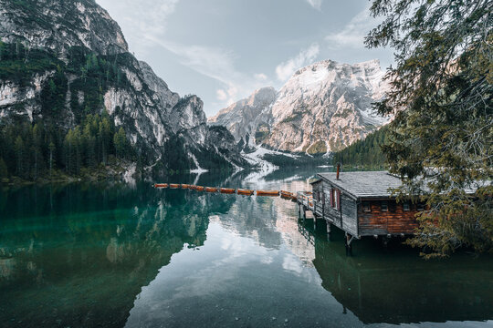 Braies, Italy - 06 June 2024: View of the iconic wooden boathouse on the emerald waters of Lago di Braies with a line of rowing boats and the majestic Seekofel mountain peak.