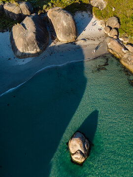Aerial view of Elephant Rocks featuring large granite boulders on a sandy beach, turquoise water, and people walking on the shore in William Bay, Western Australia, Australia.