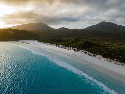 Aerial view of Hellfire Bay with white sand, turquoise water, and coastal hills under golden light in Cape Le Grand National Park, Western Australia, Australia.