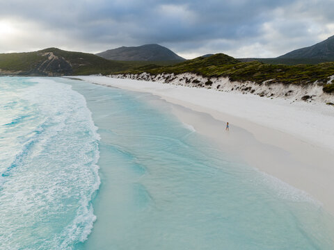 Aerial view of Hellfire Bay featuring turquoise waters, white sand, and a person walking along the shore in Cape Le Grand National Park, Western Australia, Australia.