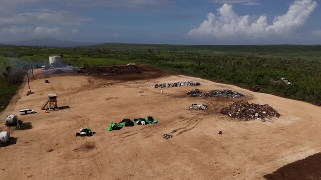 Tinian, Northern Mariana Islands - 26 June 2026: Aerial view of a waste management site with piles of scrap metal and debris on a cleared field.