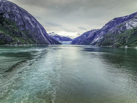 View of the calm waters of a fjord surrounded by steep, rugged mountains and a distant glacier in Ketchikan, Alaska, United States.