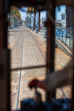 Vertical view of Embarcadero street and palm trees seen through a cable car window in San Francisco