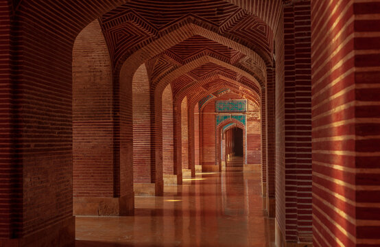 View of the red brick arches and intricate tile work inside the historic Shah Jahan Masjid in Thatta, Sindh, Pakistan.