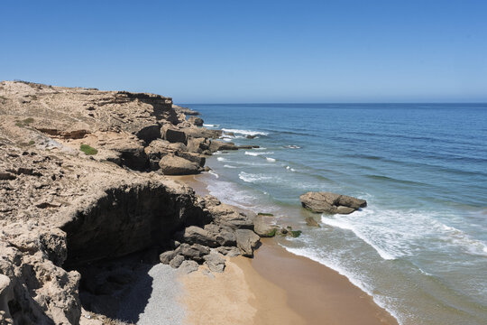 View of Mirador playa y acantilados de Tamri with rugged cliffs overlooking the sandy beach and the Atlantic Ocean under a clear blue sky in Tamri, Souss-Massa, Morocco.