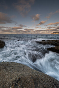 View of the rocky coastline and crashing waves at sunset in Frenchman Bay, Western Australia, Australia.