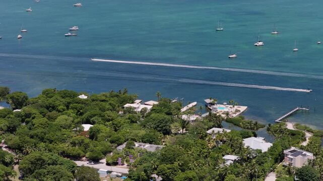Aerial view of coastal landscape with boats cruising on turquoise water, docks, and lush tropical vegetation in Islamorada, Florida, United States.