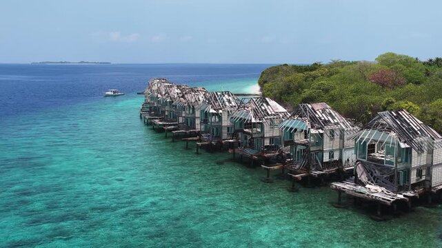 Aerial view of an abandoned luxury resort with dilapidated overwater bungalows situated above turquoise waters near Muraidhoo, Haa Alif Atoll, Maldives.