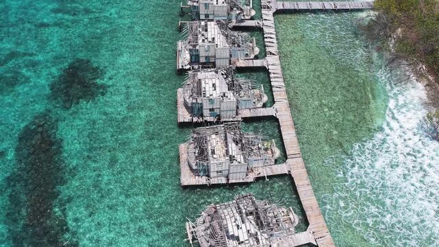 Aerial view of abandoned luxury resort with weathered wooden structures over turquoise water near Muraidhoo, Haa Alif Atoll, Maldives.