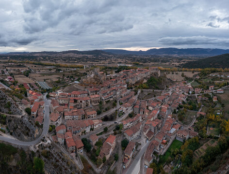 Aerial view of the historic town of Frias, featuring its medieval castle on a rocky outcrop, stone houses with terracotta rooftops, and autumn trees in Frias, Castilla y Leon, Spain.
