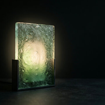 Square textured glass panel backlit by warm light on a dark metal frame