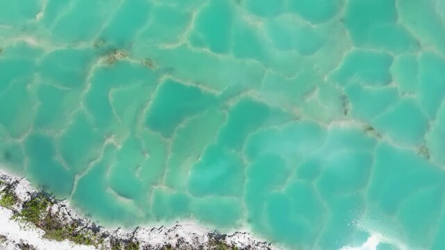Aerial view of turquoise water patterns with intricate textures and vibrant colors in Beruntung Baru, South Kalimantan, Indonesia.