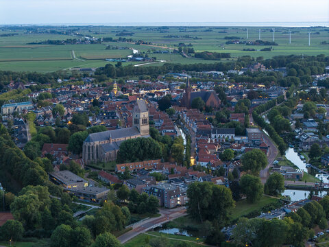Aerial view of the historic town of Bolsward featuring the Martinikerk, traditional Dutch rooftops, winding canals, and surrounding green fields in Bolsward, Friesland, Netherlands.