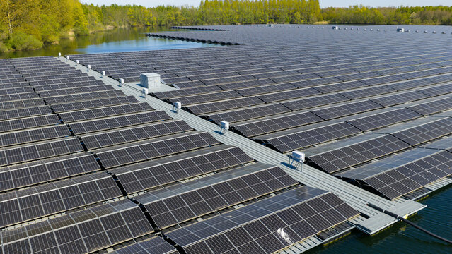Aerial view of a large floating solar farm on a lake with rows of photovoltaic panels and maintenance walkways in Zwolle, Overijssel, Netherlands.
