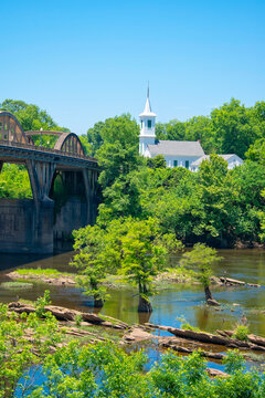 Bridge and church by the river in a green area on a sunny day