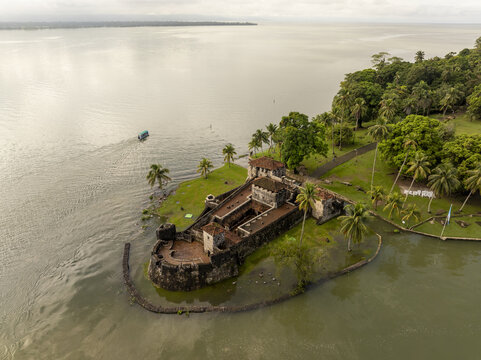 Aerial view of Castillo de San Felipe de Lara surrounded by lush palm trees and the calm waters of the river in Rio Dulce, Izabal, Guatemala.