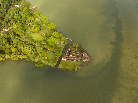 Aerial view of Castillo de San Felipe de Lara situated on the riverbank surrounded by lush green trees and water in Rio Dulce, Izabal, Guatemala.