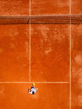 Aerial view of a tennis player on a clay court with white lines and a net in Mannheim, Baden-Wurttemberg, Germany.