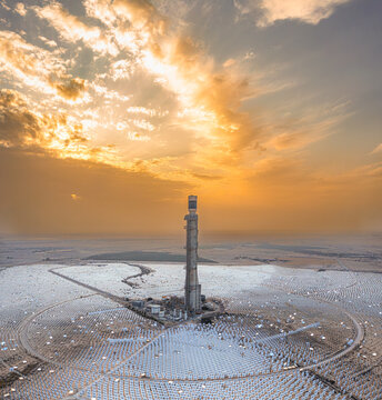 Aerial view of Ashalim Power Station with its central solar tower surrounded by thousands of mirrors in the desert landscape under a golden sunset in Beersheba, South District, Israel.